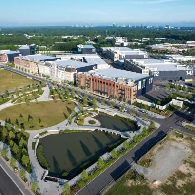 Drone shot of NBC Universal Assembly Atlanta movie studio that has buildings with numbers on them as well as greenery, trees, sidewalks, and a pond
