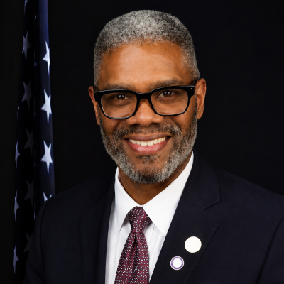 Zach Williams, Chief Operating Officer, official portrait wearing a DeKalb County pin, in front of an American flag.