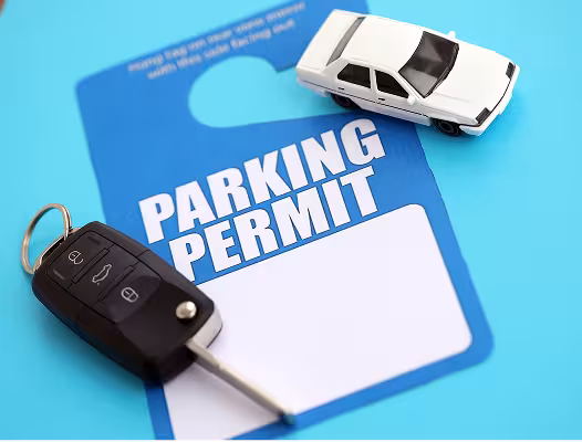 A blue parking permit on a blue background with a white toy car and a key fob for a car.