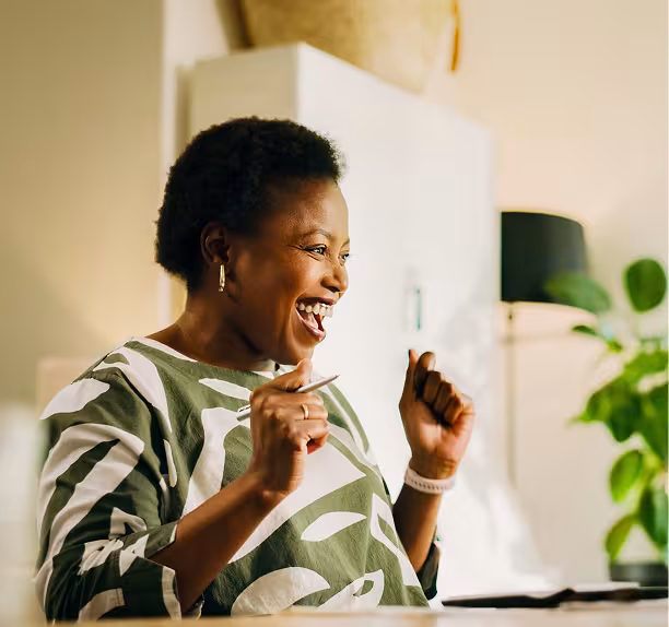 Woman with short black hair and a green and white shirt with a white watch celebrating.