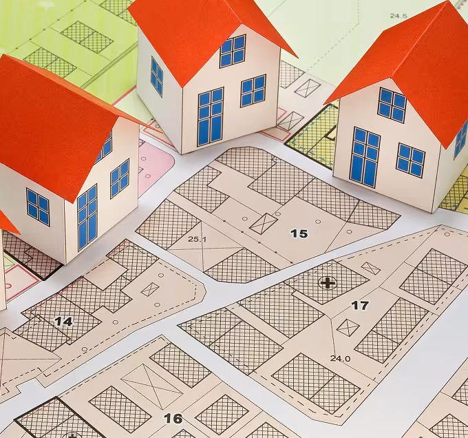 Colorful 2D blueprint of a neighborhood that is beige and green. There are three 3D houses with red roofs, blue windows, and beige walls.