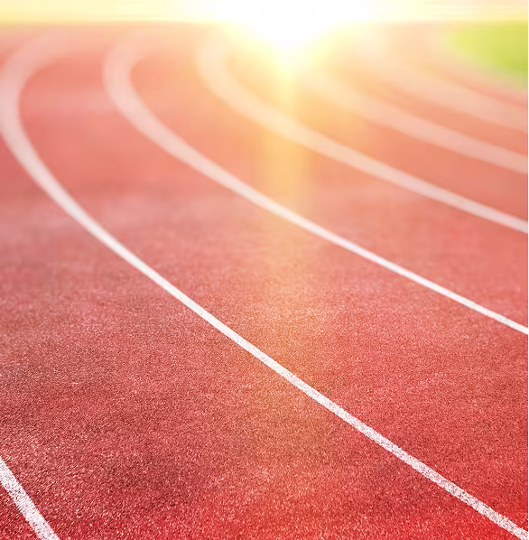 A sunlit running track with multiple red lanes curves smoothly to the horizon. The bright sunlight creates a warm, hopeful atmosphere.