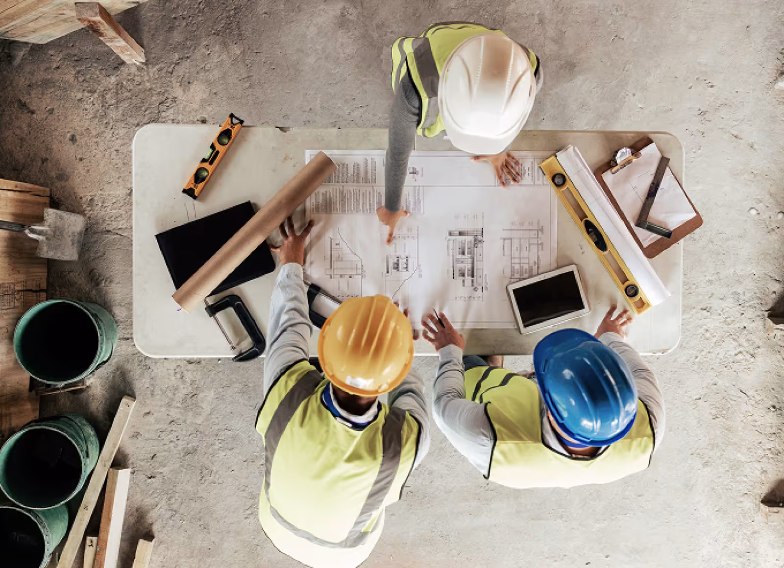 Construction workers looking over a blueprint with equipment on the table, such as a level.