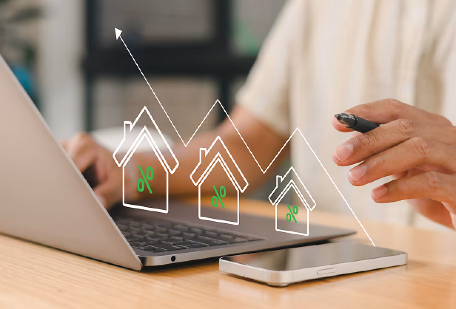 A person working with a silver laptop and phone in front of them and a graph line with several basic home icons under it with green percentage symbols inside of the homes.