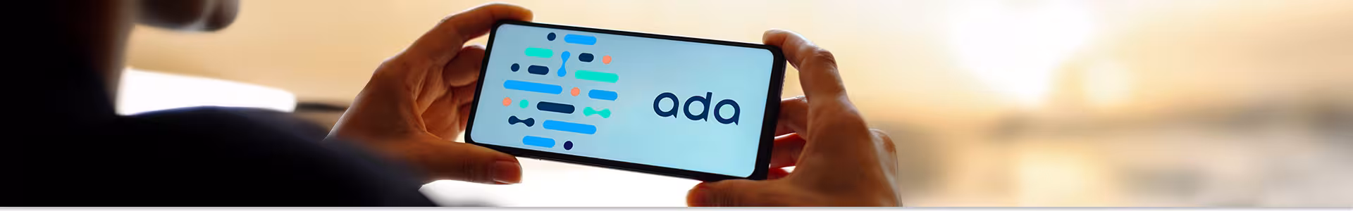 Person looks at their phone in a horizontal view with "ada" written in blue and a series of large font lines in blue, black, orange, and lime green on a white background.